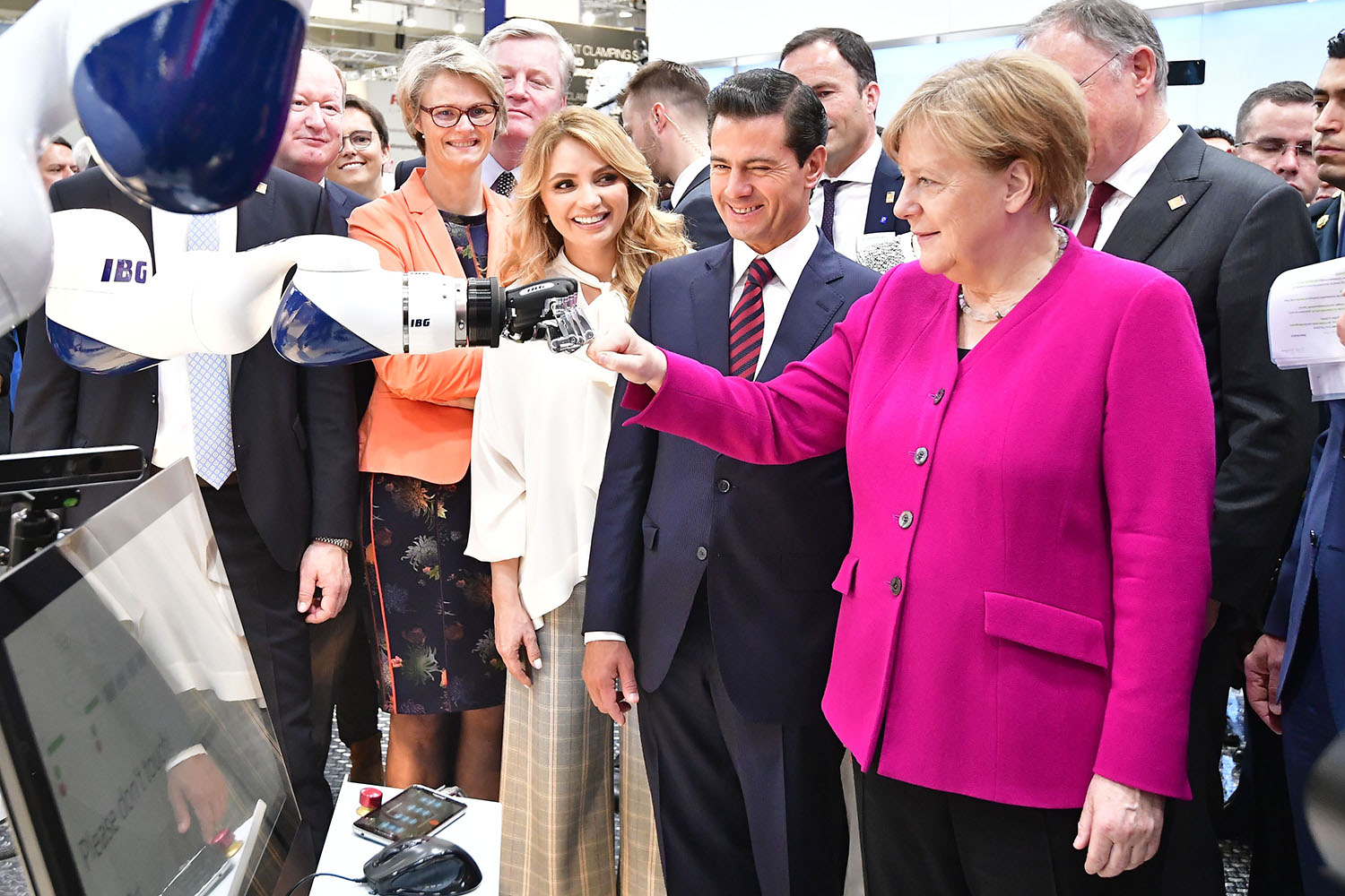Then-German Chancellor Angela Merkel greets a robot next to then-Mexican President Enrique Peña Nieto as they visit the IBG Automation stand during the Hannover Messe technology fair in Hanover, Germany, on April 23, 2018.
