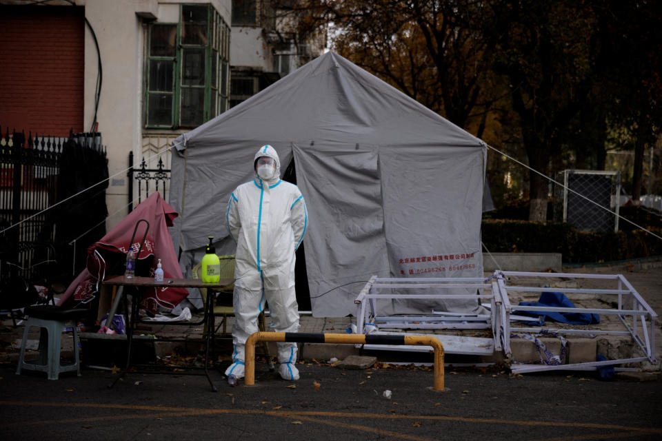 An epidemic prevention worker wearing a protective suit stands outside a residential complex that has been placed under lockdown as the coronavirus disease (COVID-19) outbreak continues in Beijing, China November 12, 2022. REUTERS/Thomas Peter
