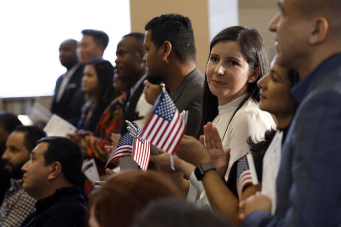 people hold us flags at naturalization ceremony