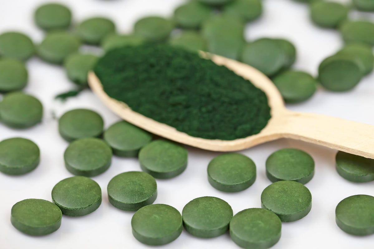 A spoonful of spirulina, on top of the spirulina tablets.
