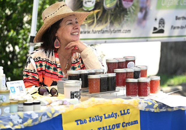 Karen Castranova talks with customers Tuesday, April 23, 2024, at her booth, The Jelly Lady, LLC, during the first day of this season's West Loveland Farmers Market in the Jack's parking lot.  They also sell Aspen Glo TALLOW Cream and Colorado Cabin Candles.  (Jenny Sparks/Loveland Reporter-Herald)